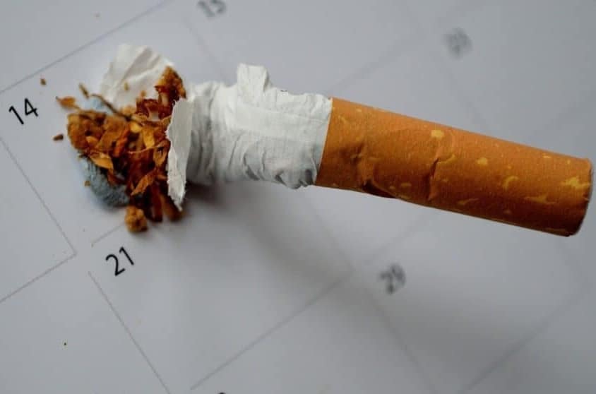 A stubbed out, unlit, white filter cigarette on a calendar with the date of 14th.  This is a designated day to quitting smoking.