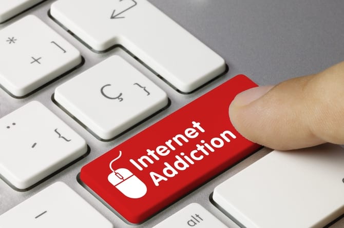 Behavioural addiction such as internet dependency destroys individual's life. The picture shows computer keyboard with finger pressing a red button with the inscription "Internet addiction"