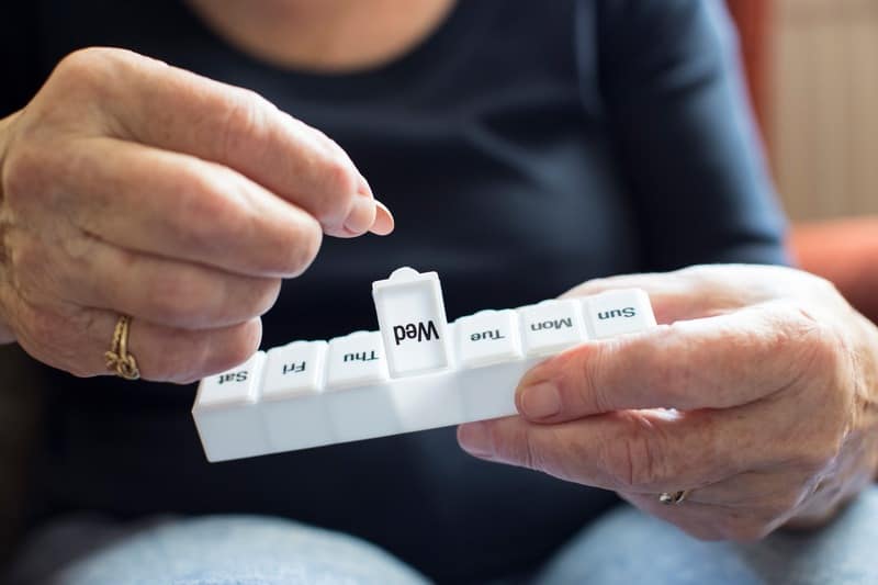 Bipolar disorder, treatment with medication. Man is taking a tablet form a box.