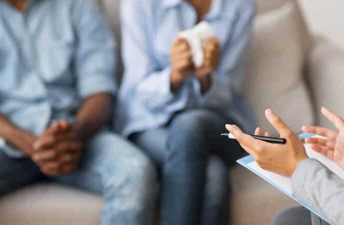 Marriage counselling: Man and women sitting in the front of a therapist during a session of couple counselling