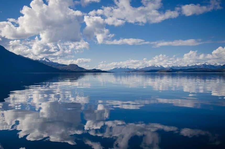 Hypnosis. Blue sky and clouds reflected in the water surrounded by mountains. What lies beneath the water represents the unconscious mind that hypnosis and clinical hypnotherapy focuses on.