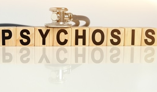 Psychosis is a set of symptoms which can appear in different mental disorders. The picture shows cubes with the words "psychosis" and a stethoscope to depict the medical specialty of psychiatrist.