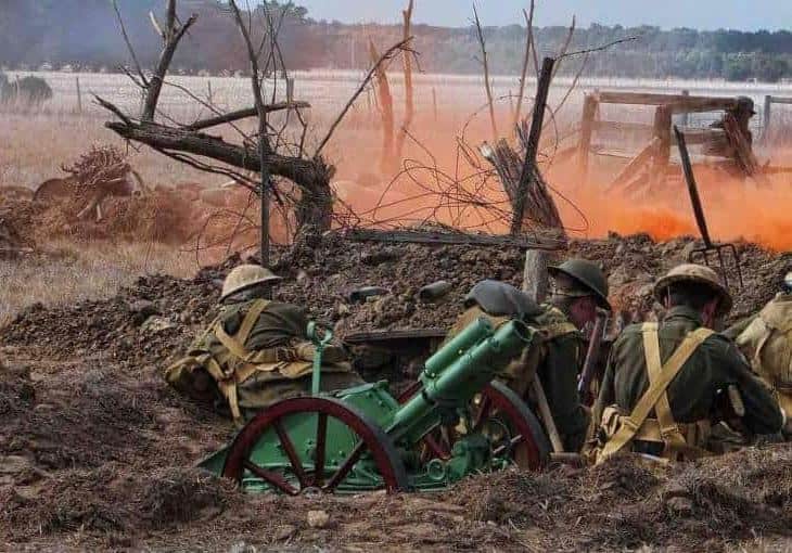 Facts PTSD. Picture shows British soldiers in the tranches of WW I. The soldiers stand in a trench next to a canon. One soldier is running with his guns into attack. The air is covered by dust