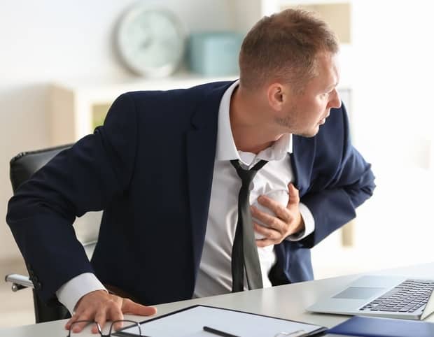 Panic attacks symptoms diagnosis. The picture shows an anxious man sitting on the desk  with hand on his chest 